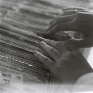 Hands Browsing Through A Pile Of Vintage Magazines In A Retro Black And White Photo.
