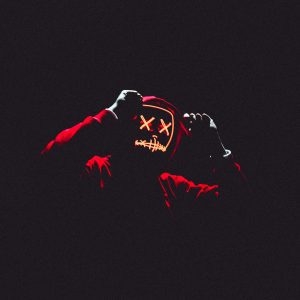 A Person In A Glowing Neon Mask And Hoodie In A Dark, Ominous Setting.