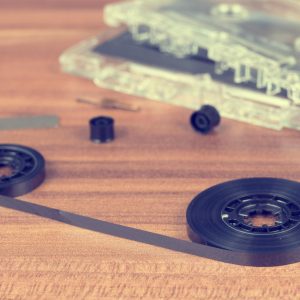 Disassembled Cassette Parts On Wooden Table Create A Vintage Tech Aesthetic.