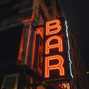 Illuminated Vintage Neon Bar Sign In An Urban Street At Night, Creating A Nostalgic Vibe.