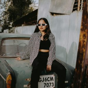 Young Woman In Trendy Sunglasses Poses With A Classic Car, Exuding Retro Charm.