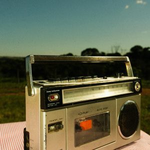 Retro Cassette Player On A Red Checked Tablecloth With Rural Outdoor Backdrop.