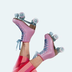 Vibrant Pink Roller Skates With Legs In Red Striped Pants On A White Backdrop.
