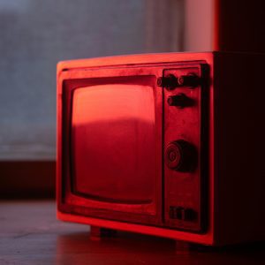 A Vintage Television Set Illuminated By Red Light, Showcasing Nostalgic Technology Indoors.