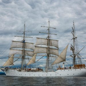 A Stunning View Of A Classic Sailing Ship Navigating The Waters Of Hol, Norway, Under A Dramatic Sky.