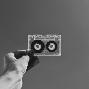 Hand Holding A Classic Cassette Against A Plain Backdrop In Black And White.