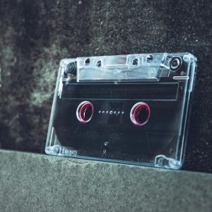 A Clear Cassette Tape Resting On A Concrete Surface Evokes A Vintage And Nostalgic Vibe.