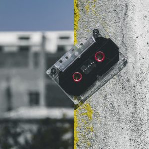 Close Up Of A Classic Cassette Tape Against A Textured Concrete Wall Outdoors.
