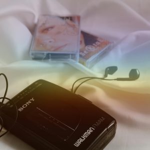 Close Up Of A Retro Sony Walkman With Cassette Tape And Earphones On A White Sheet.