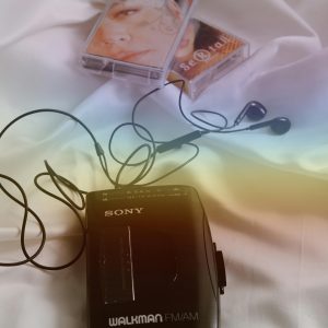 Vintage Walkman With Cassette Tapes And Earphones On White Cloth, Evoking Nostalgia.