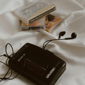 Retro Walkman With Cassette Tapes And Earbuds On White Fabric, Evoking Nostalgia.