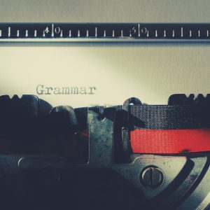 A Detailed Close Up Of A Vintage Typewriter Typing The Word 'Grammar'.