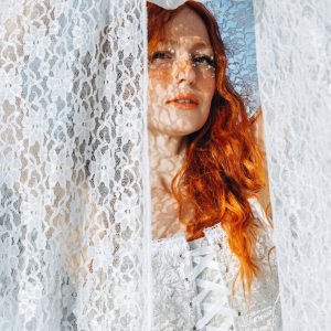 Portrait Of A Woman In A Lace Dress With Red Hair, Casting Intricate Shadows Outdoors.