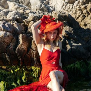 A Woman In A Red Dress Poses Elegantly By A Rocky Seaside In Türkiye.