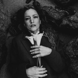 A Dramatic Black And White Portrait Of A Woman Holding Lilies, Offering An Artistic And Emotional Expression.