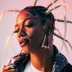Vibrant Portrait Of A Stylish Woman With Creative Hairstyle And Big Earrings, Holding A Lighter.