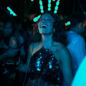 Woman In Sequined Dress Laughing And Dancing In A Vibrant Nightclub Setting.