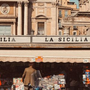 Charming Sicilian Street Scene With A Kiosk, Scooter, And Historic Architecture.
