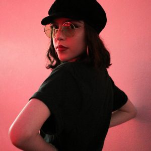 Elegant Woman In Retro Style Sunglasses Posing With A Pink Background.