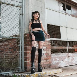Gothic Fashion Portrait Of A Woman In Urban Environment With Fishnet Tights And Thick Boots.
