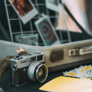 Vintage Canon Camera Surrounded By Polaroid Photos And Travel Essentials In A Cozy Setting.