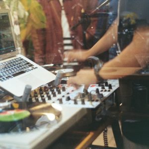 DJ Playing Vinyl Records With Hands On Mixing Panel And Laptop In A Studio.