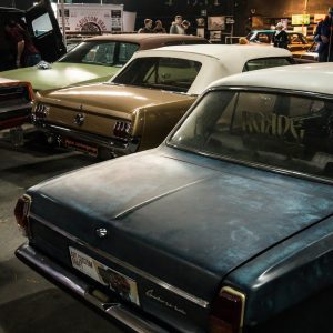 Explore A Classic Car Show Indoors Featuring Vintage Sedans And Automotive Enthusiasts.