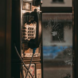 A Vintage Telephone Booth With A Rusty Exterior On An Urban Street.