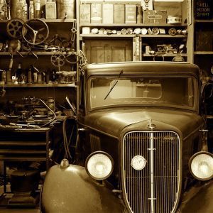 A Vintage Car Surrounded By Antique Tools And Parts In A Nostalgic Workshop.