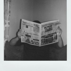 Person Reading A Newspaper At Home In A Vintage Black And White Style.
