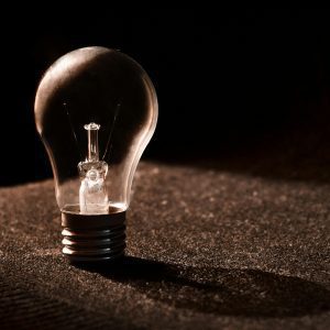 Close Up Of A Light Bulb Against A Dark Background, Showcasing Shadows And Reflections.