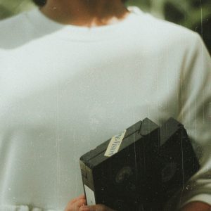 A Woman In Vintage Style Holds VHS Tapes, Evoking Nostalgia.