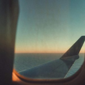 View Of A Sunset Through An Airplane Wing Window, Flying Over The Sea.