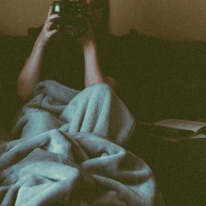 Woman Wrapped In A Blanket Photographing Indoors, Capturing A Cozy Moment.