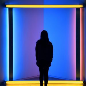 A Woman Stands Silhouetted Against Vibrant Neon Lights, Creating A Colorful Visual Impact.