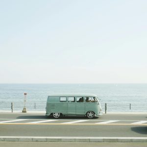 A Classic Volkswagen Van Driving On A Seaside Road In Fujisawa, Japan, Capturing A Nostalgic Coastal Vibe.