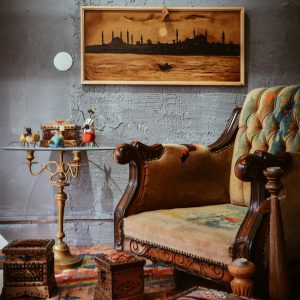 Cozy Living Room With A Vintage Armchair, Artistic Wall Art, And Wooden Decor.