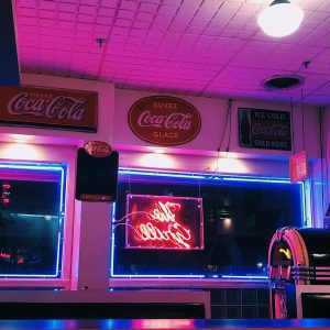 A Vibrant Retro Diner In Athens, GA, Featuring Vintage Coca Cola Signs And Neon Lights.