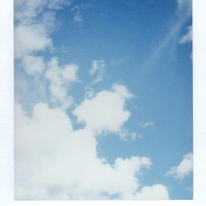 Bright Blue Sky With Fluffy Clouds Captured In A Vintage Polaroid Style.