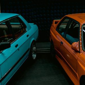 Close Up Of Vintage BMW E28 And E30 Models Displayed At An Indoor Car Exhibition.
