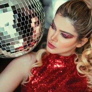 A Glamorous Woman In A Red Dress Poses With A Disco Ball, Showcasing Fashion And Beauty.