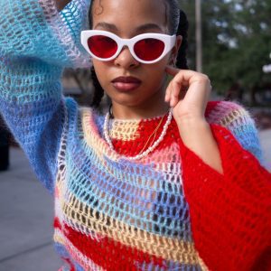 Fashionable Woman Poses In Colorful Knitwear And Red Sunglasses Outdoors.