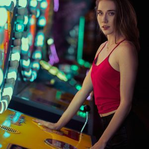 Stylish Woman In Red Top At An Illuminated Arcade, Enjoying A Fun Night Out.