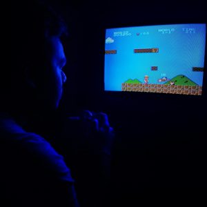 Man Playing Super Mario Bros On TV, Capturing Retro Gaming Nostalgia.
