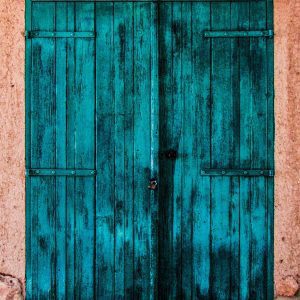 A Vibrant, Rustic Blue Wooden Door On A Textured, Weathered Wall.