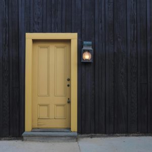 A Modern Yellow Door On A Dark Wooden Facade Creates A Striking Contrast. Architectural Detail.