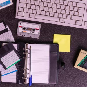 A Nostalgic Setup With Vintage Electronics Like A Walkman, Floppy Disks, And A Typewriter Keyboard.