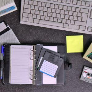 Flat Lay Of Retro Office Supplies Featuring A Walkman, Floppy Disks, Keyboard, And Planner.