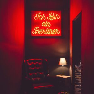 Stylish Dimly Lit Interior Featuring A Neon Sign Above A Leather Armchair And Table Lamp.