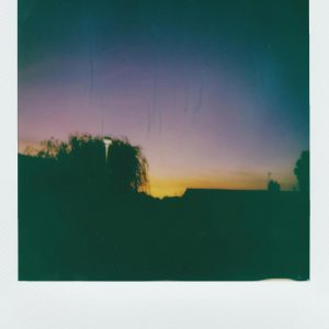 A Vintage Instant Film Photo Capturing A Silhouette Against A Vibrant Sunset.